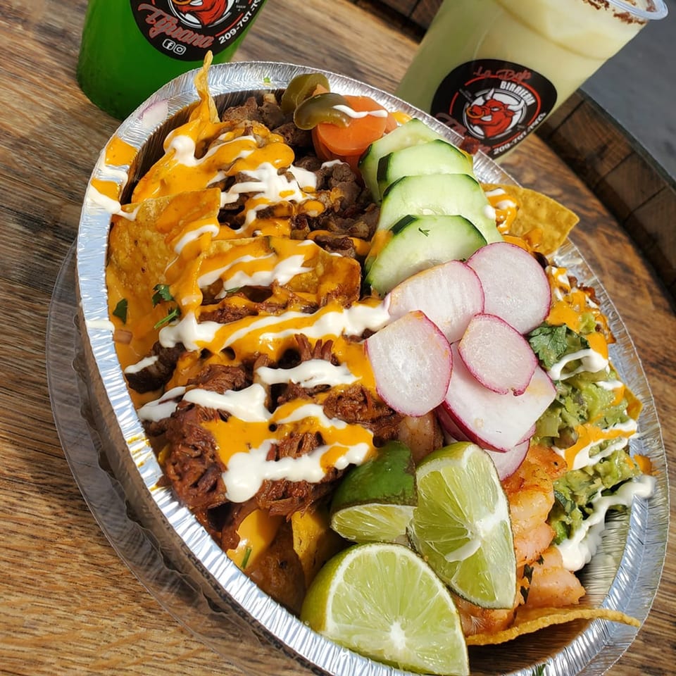 La Baja Birreria's loaded nachos with meat, cheese, guacamole, radishes, cucumbers, and limes.