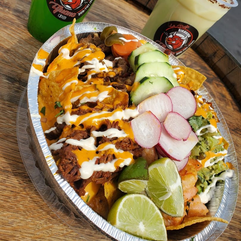 La Baja Birreria's loaded nachos with meat, cheese, guacamole, radishes, cucumbers, and limes.